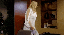 a woman in a white top is standing in front of a shelf with a picture on it