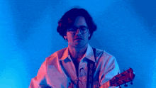 a man wearing glasses is playing a guitar