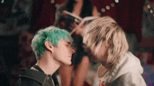 two young men with green hair are looking at each other .