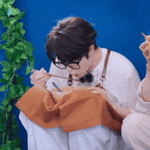 a person wearing glasses is eating a bowl of soup with chopsticks