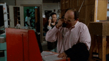a man in a pink shirt is talking on a phone with a woman