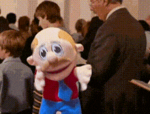 a man in a suit is standing next to a stuffed toy with a mustache