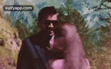 a man in a suit and tie is hugging a woman in a pink dress in front of a painting .