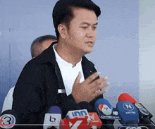 a man stands in front of a row of microphones including one that says cntv news
