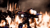 a group of robots are standing in front of a large fire .
