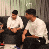two men are sitting on a couch and one has a question mark above his head