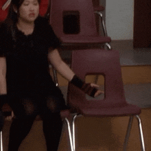 a woman in a black dress sits in a chair