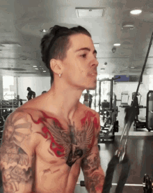 a shirtless man in a gym with a tattoo on his chest