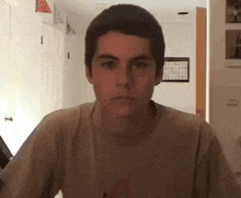a young man wearing a t-shirt is looking at the camera .