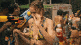 a woman in a bikini is being sprayed with water by a man holding a water gun