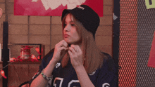 a woman wearing a black hat that says ' shirts ' on it