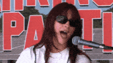 a woman is singing into a microphone in front of a sign that says party