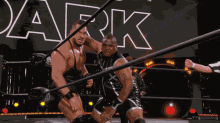 two wrestlers are in a ring with the word dark behind them