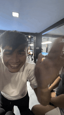 a man in a white shirt is smiling and giving a thumbs up