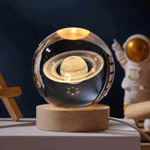a glass ball with a light inside of it is sitting on a table next to an astronaut statue .