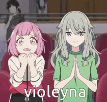 a couple of anime girls sitting next to each other in a theatre .