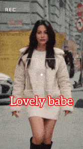 a woman in a white dress is being recorded by a camera with the words lovely babe above her