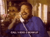 a man with a beard is laughing while talking on a telephone