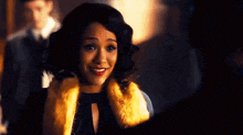 a woman is wearing a fur coat and smiling while standing next to a man .