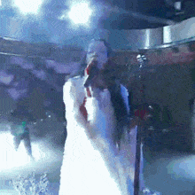 a woman in a white dress singing into a microphone on stage