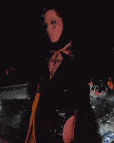 a woman with a cross on her chest is standing in a dark room