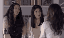 two women are sitting at a table talking to each other .
