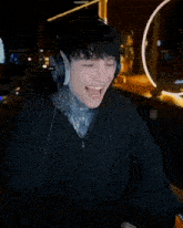 a man wearing headphones laughs in front of a poster that says kick and cry
