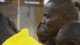 a group of men huddled together with one wearing a yellow sweater