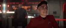 a man in a red jacket holds his finger to his lips in front of a sign that says vamonos