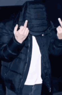 a man wearing a black jacket and a white shirt is giving the middle finger