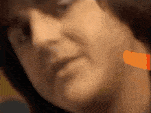 a close up of a woman 's face with a blurred orange stripe on her neck
