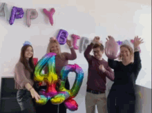 a group of people are holding balloons in front of a happy birthday sign .