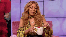 a woman is sitting in a chair holding a wendy coffee cup .