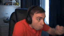 a man wearing headphones and a red shirt is making a funny face