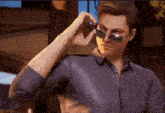a man wearing sunglasses and a blue shirt adjusts his glasses
