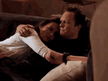 a man and a woman are sitting on a couch hugging each other .