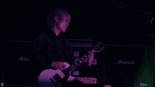 a person playing a guitar in front of a marshall amplifier