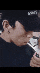 a man wearing a black hat with the word jaru on it smoking a cigarette .