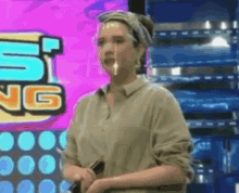 a woman with a bandana on her head is standing in front of a sign that says ' sing ' on it .