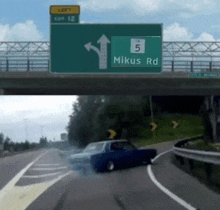a green highway sign that says mikus rd is above a car