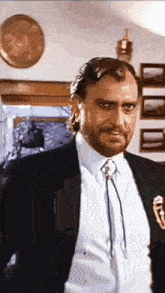 a man with a beard wearing a suit and tie looks at the camera