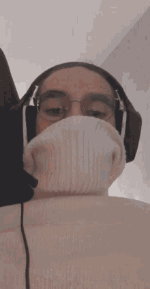 a person wearing headphones and a turtleneck sweater covering their face