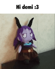a stuffed animal with purple hair and horns is sitting on a table under a sign that says hi demi 3