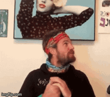 a man wearing a headband is standing in front of a picture of a woman