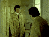 a man in a trench coat is standing next to another man