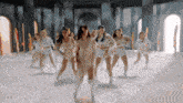 a group of young women are dancing in a room with columns .