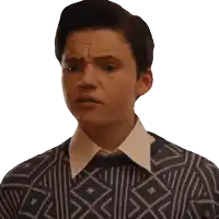 a young man wearing a sweater with a geometric pattern on it makes a funny face
