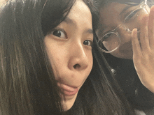 a girl wearing glasses is making a funny face next to another girl