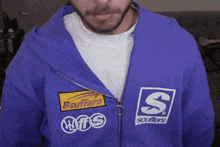 a man is wearing a purple sweatshirt with a scuffers logo on it