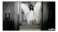 a woman in a white dress with angel wings is standing in a doorway .